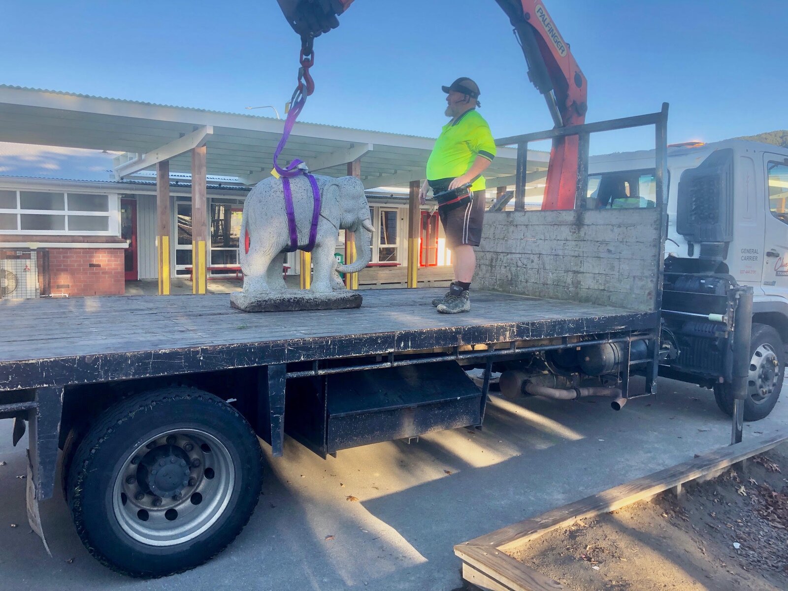 CDT Transport HIAB crane swinging a large stone elephant sculpture into a school playground, Wellington