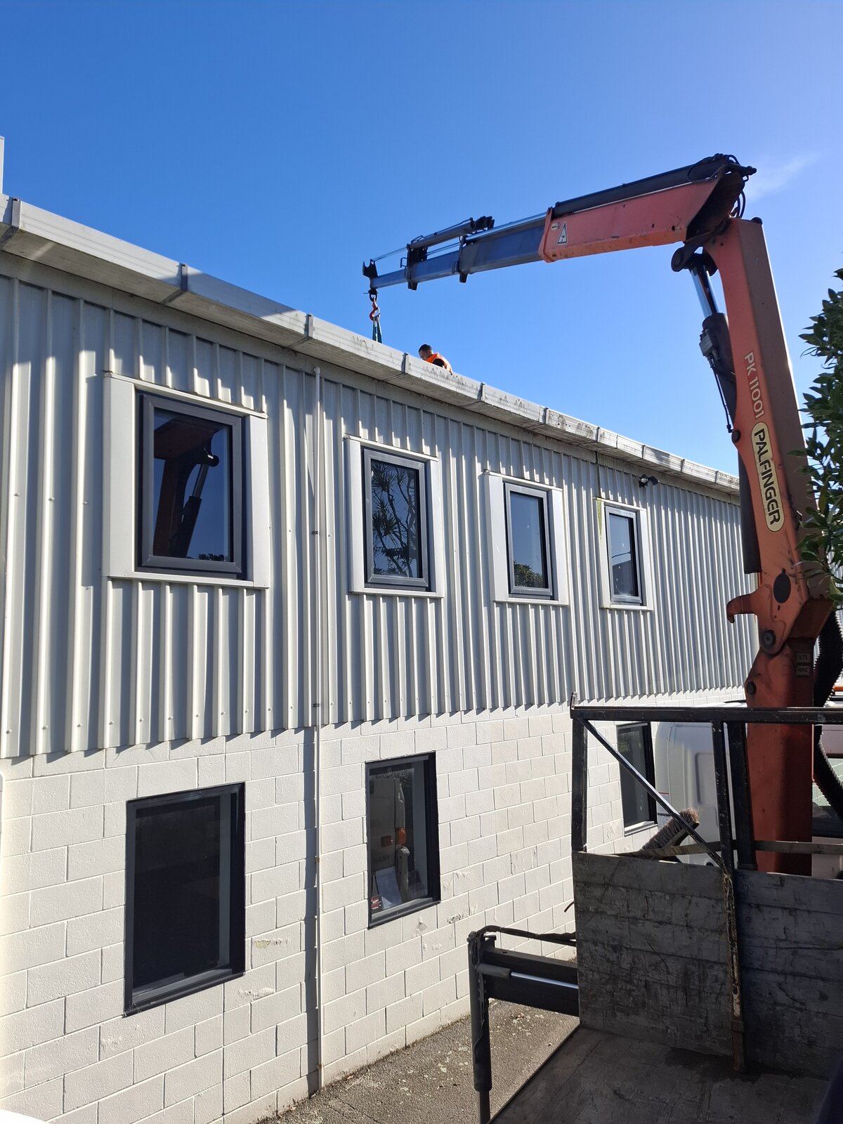 HIAB truck hire Wellington - Palfinger PK 11001 crane arm extended over a rooftop lift