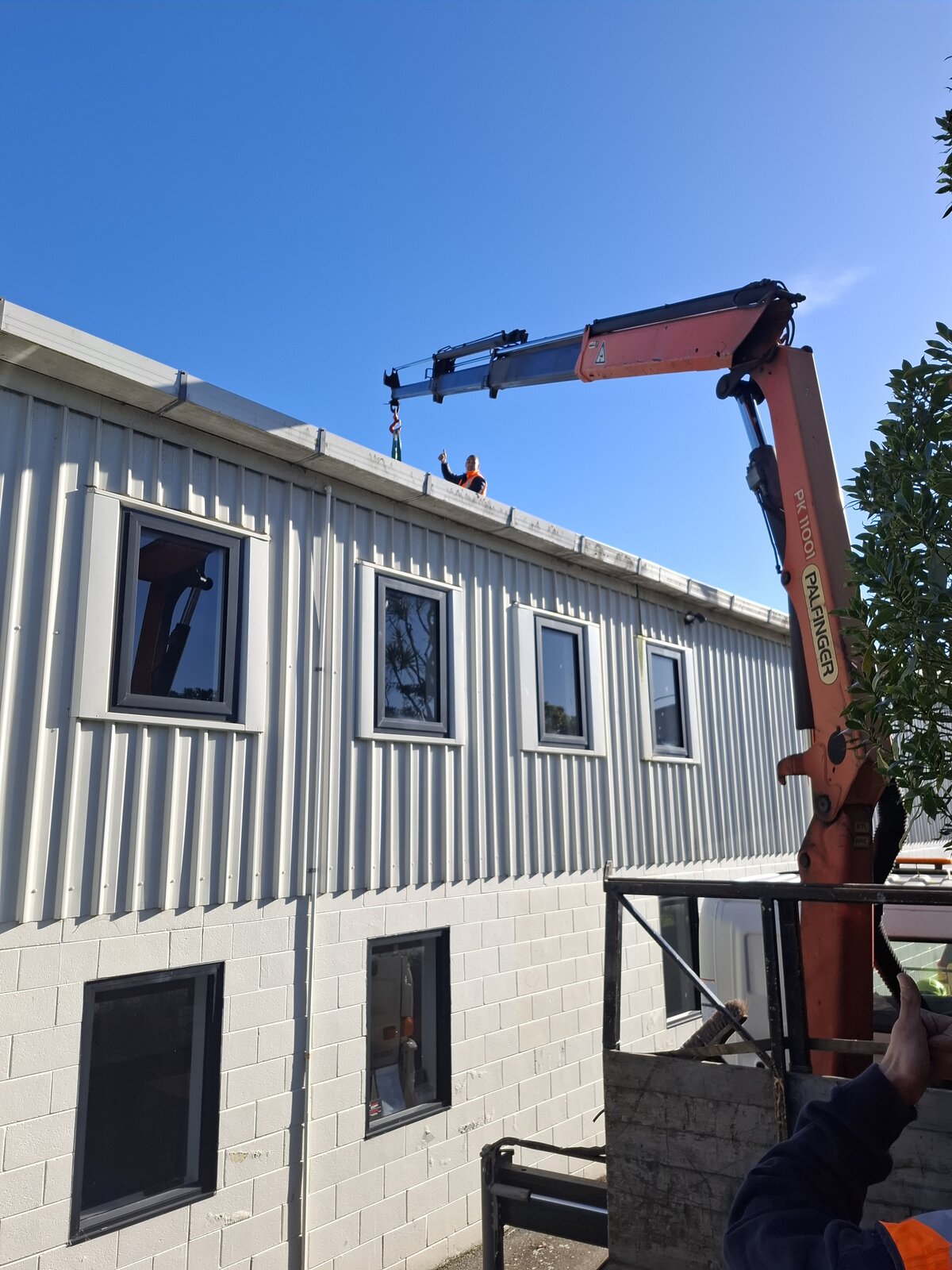 CDT Transport HIAB crane truck lifting a heat pump unit onto a rooftop in Wellington
